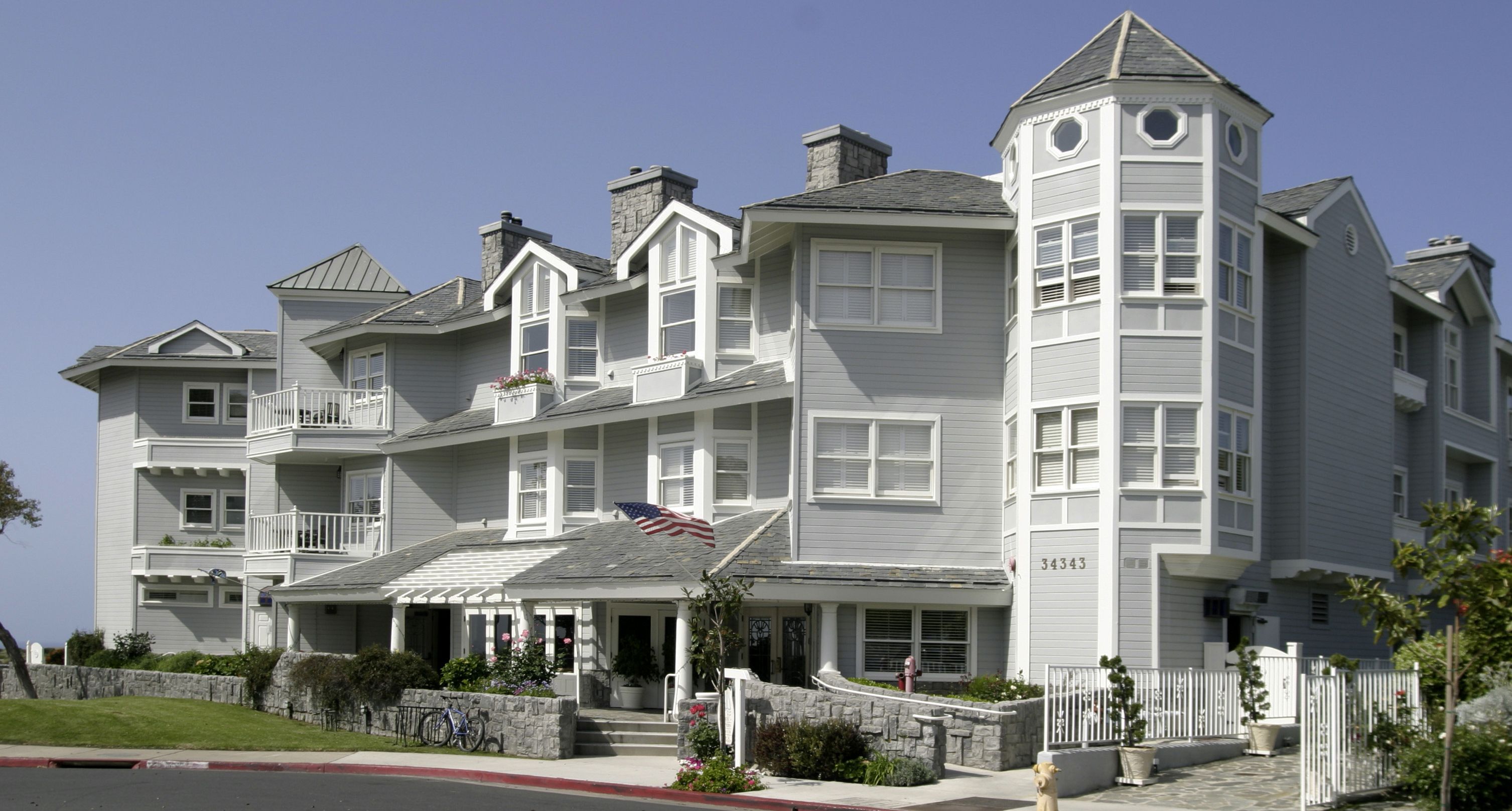 A large, multi-story building with a prominent tower, a flag, and a stone wall.