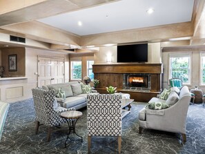 A spacious living room with a fireplace, comfortable seating, and large windows.