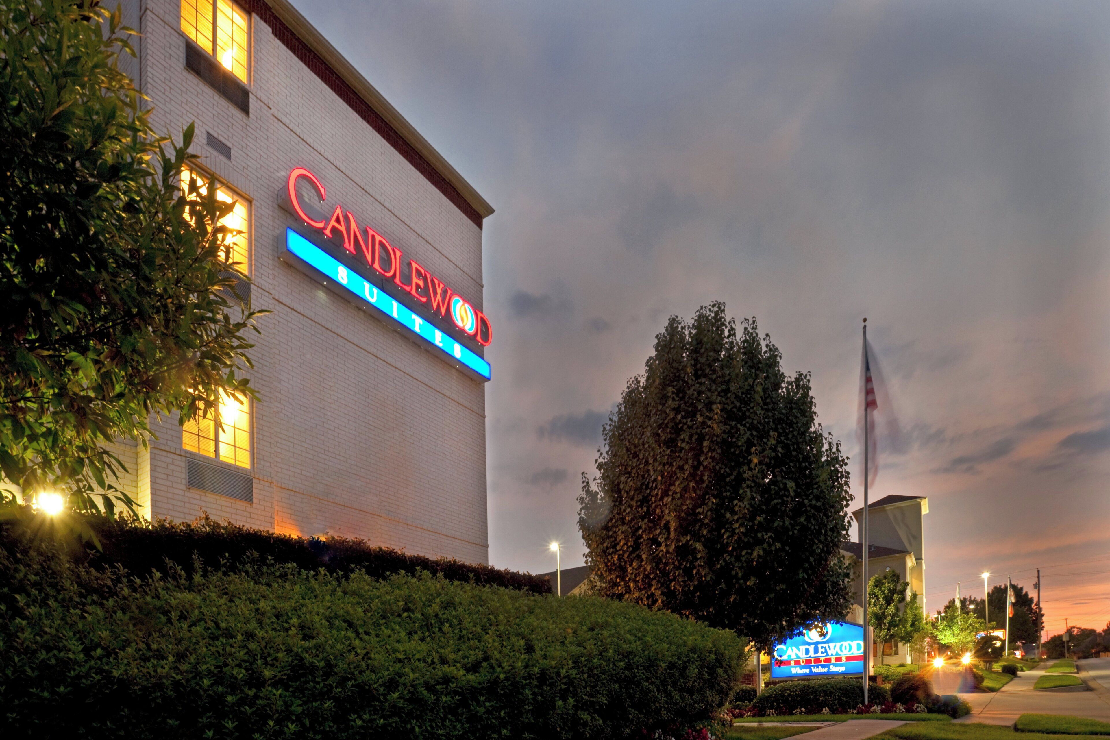 A hotel with a prominent 'CANDLEWOOD' sign, a flagpole, and well-maintained landscaping.