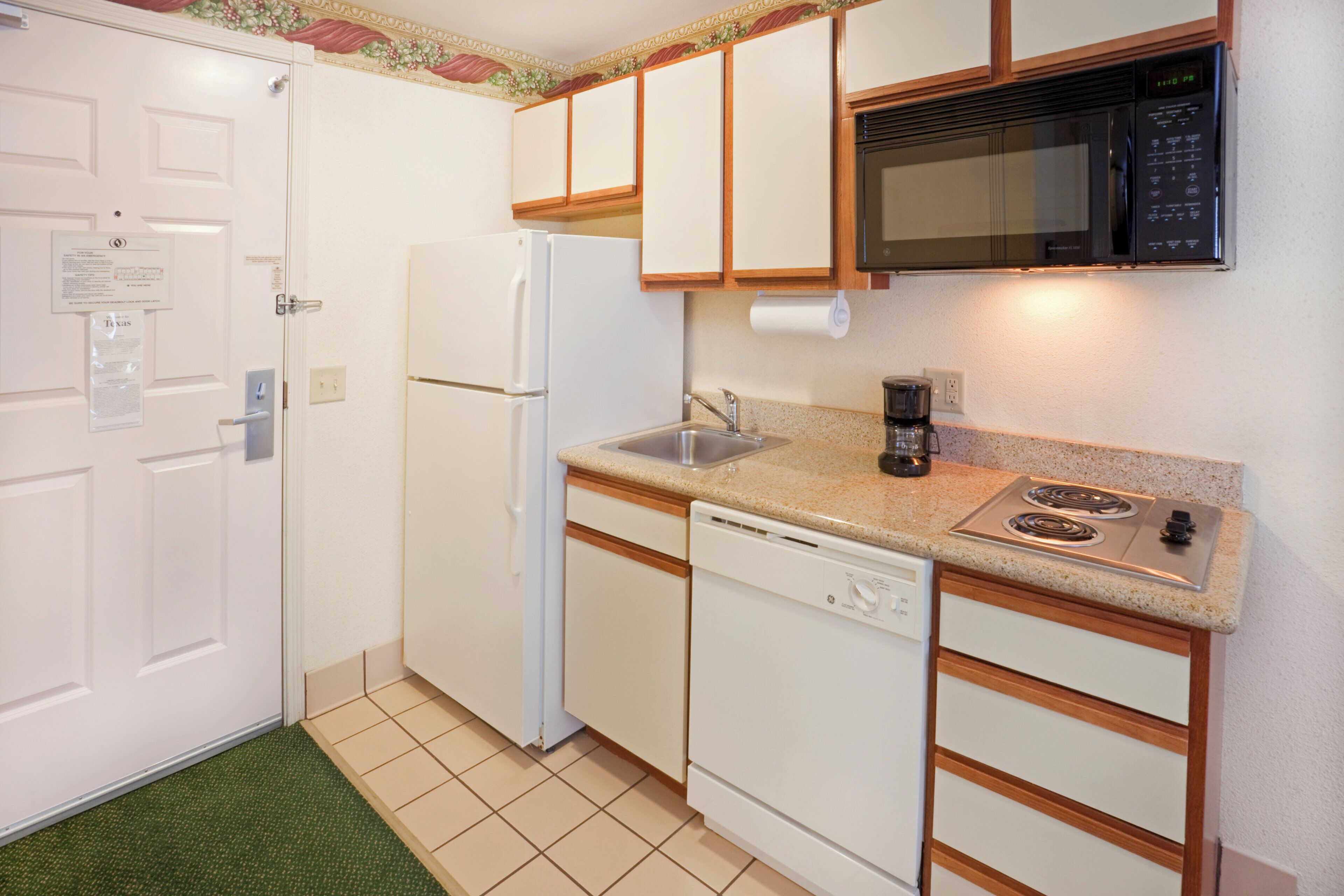 A compact kitchen with a refrigerator, microwave, sink, and dishwasher.