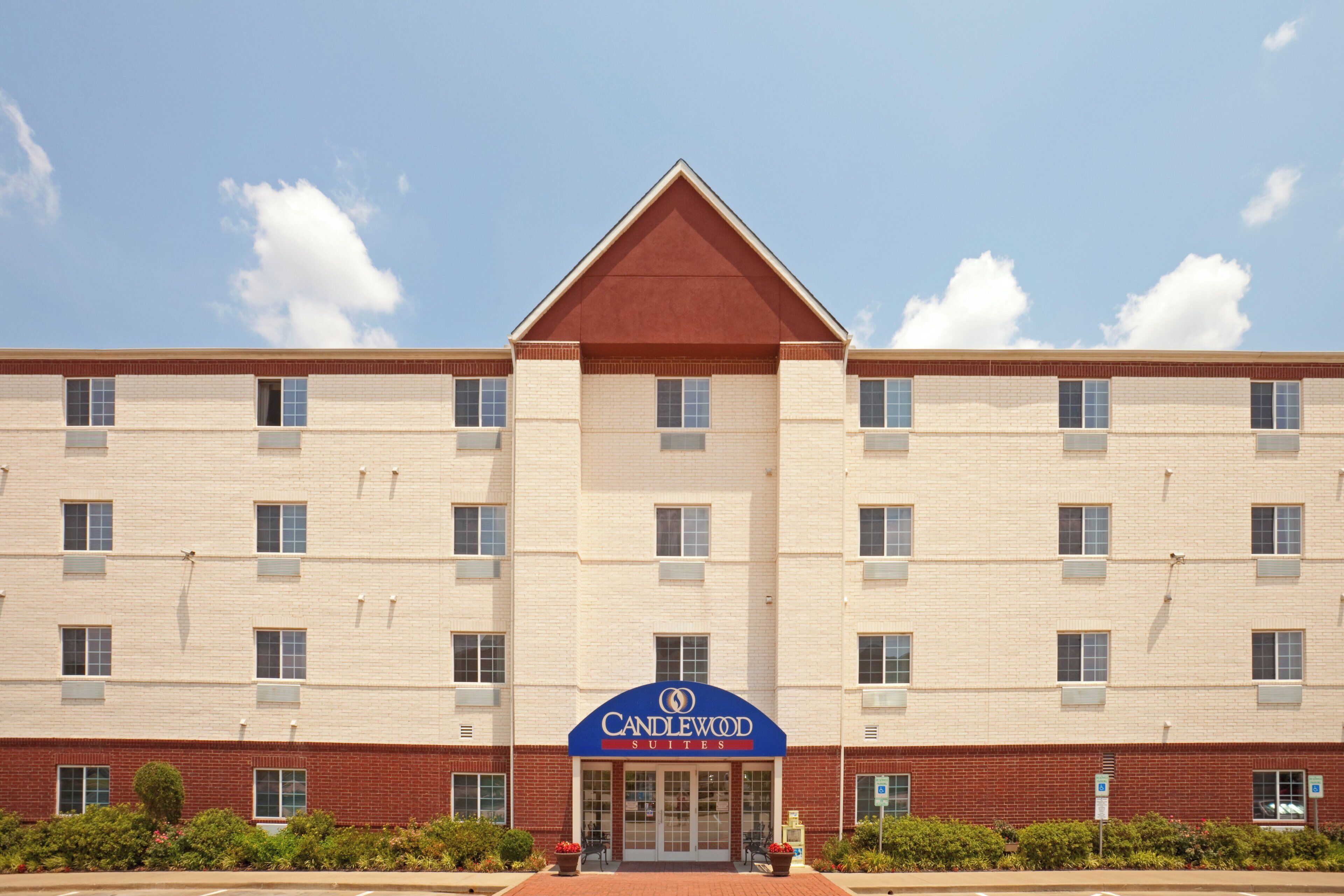 A hotel with a red roof and a blue sign reading 'Candlewood Suites.'