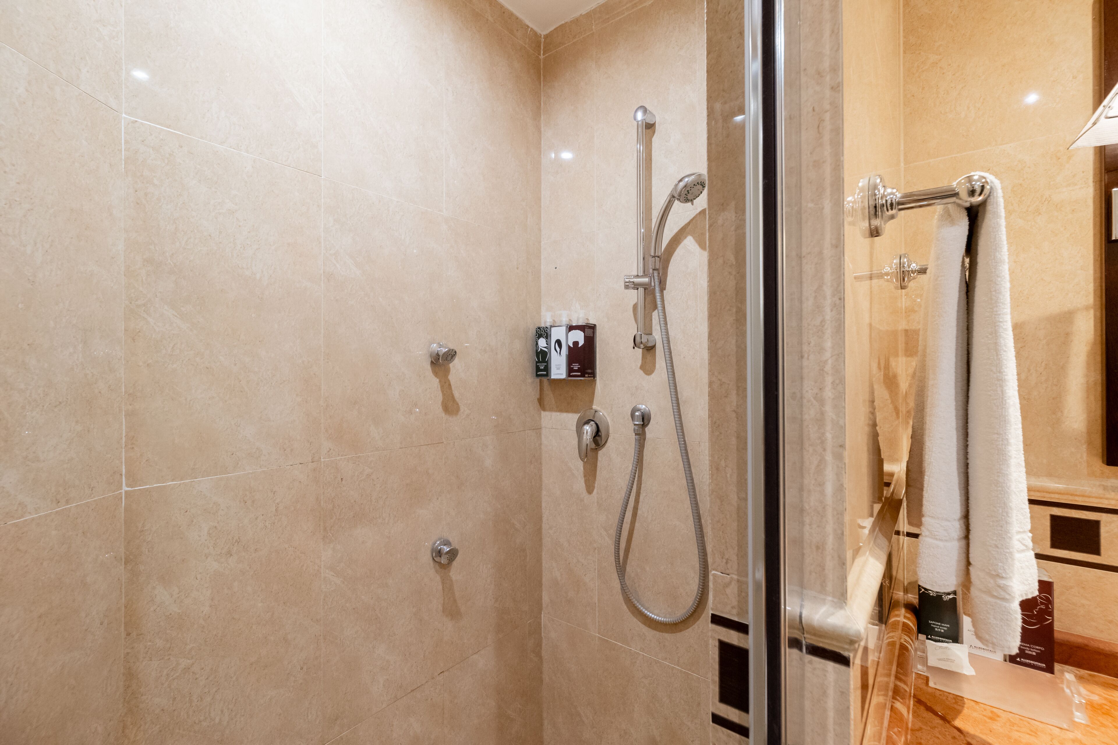 A modern bathroom with a glass shower enclosure, a towel rack, and a marble floor.