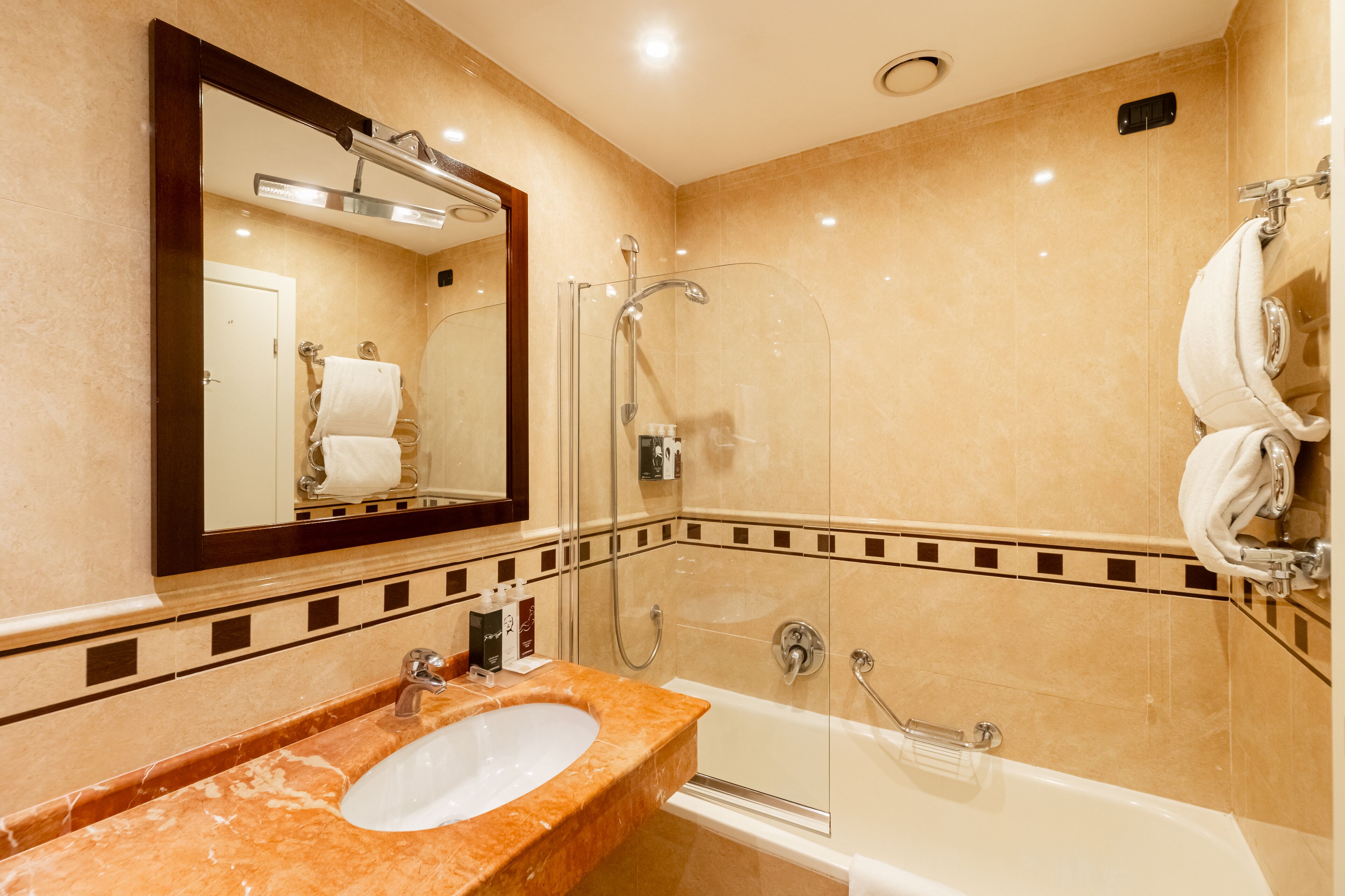 A modern bathroom with a marble sink, a glass-enclosed shower, and a large mirror.