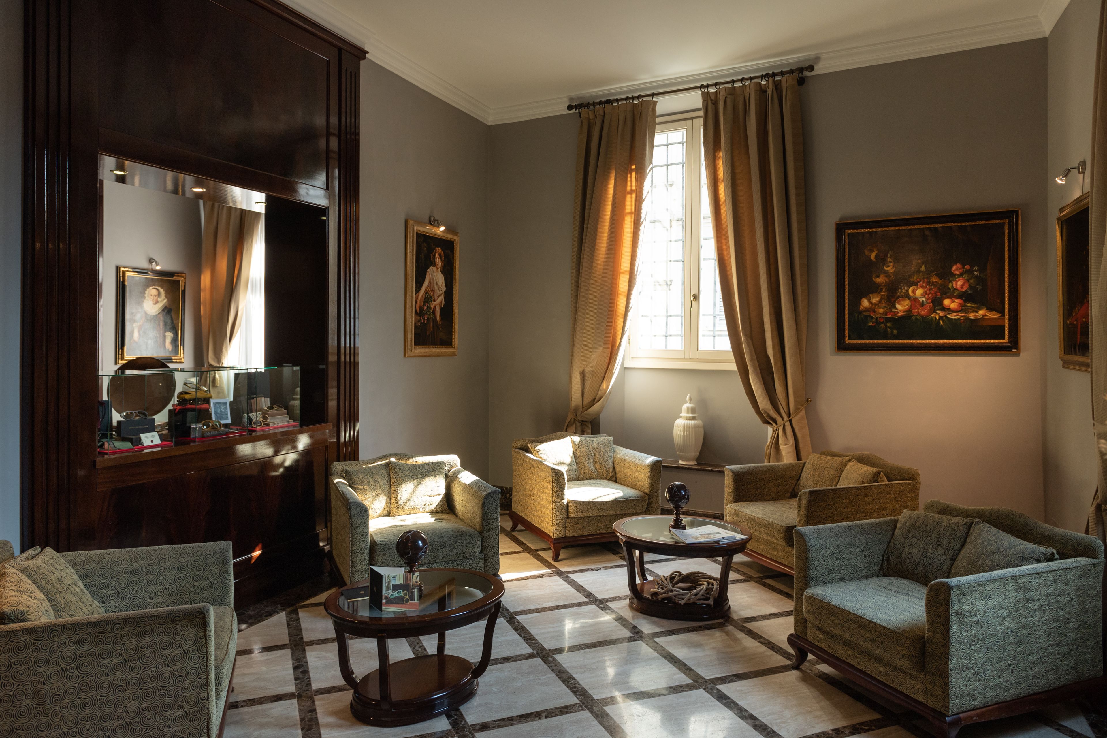A living room with a checkered floor, two armchairs, a sofa, a coffee table, and a painting on the wall.