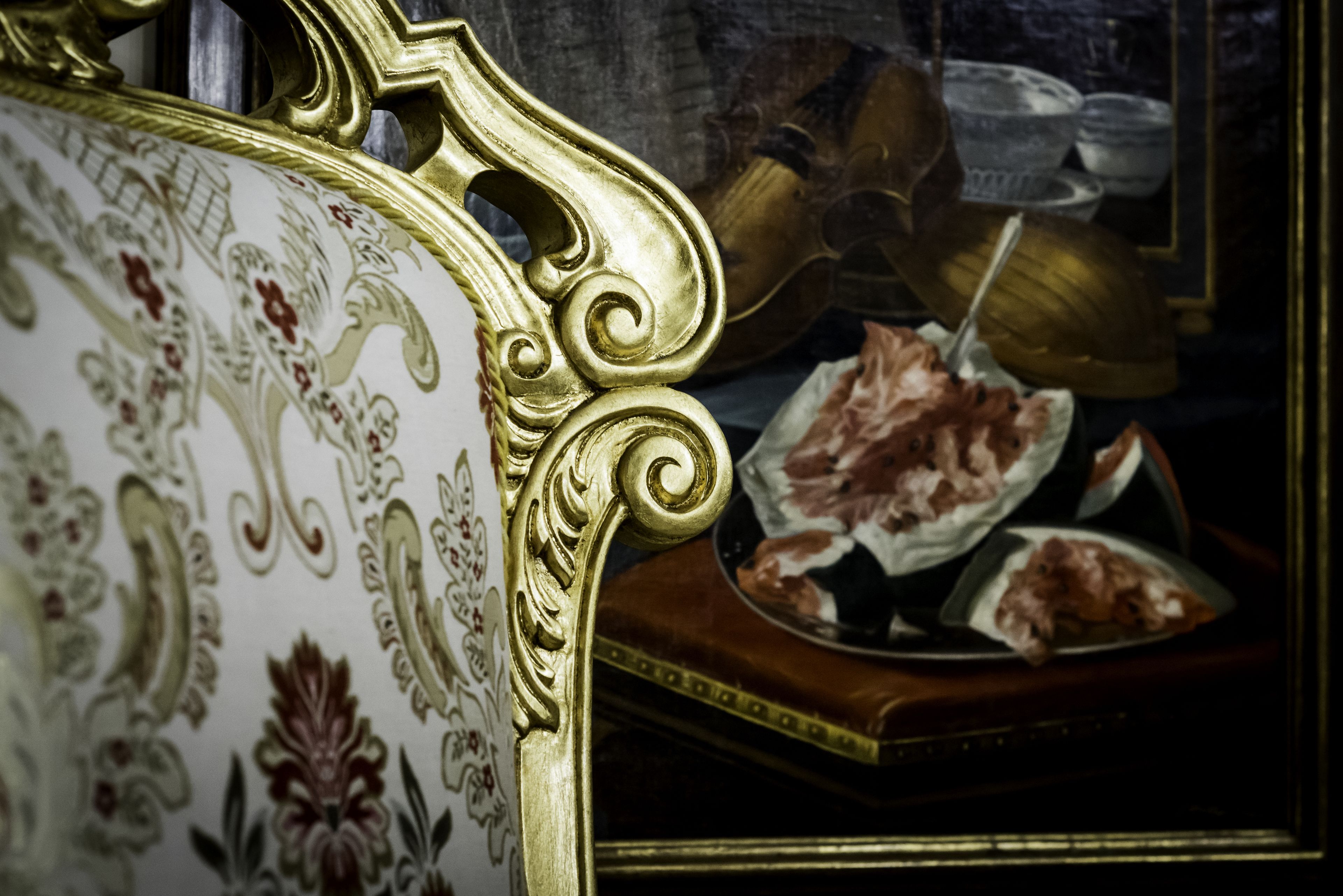 A close-up of an ornate, gold-trimmed chair with intricate patterns.
