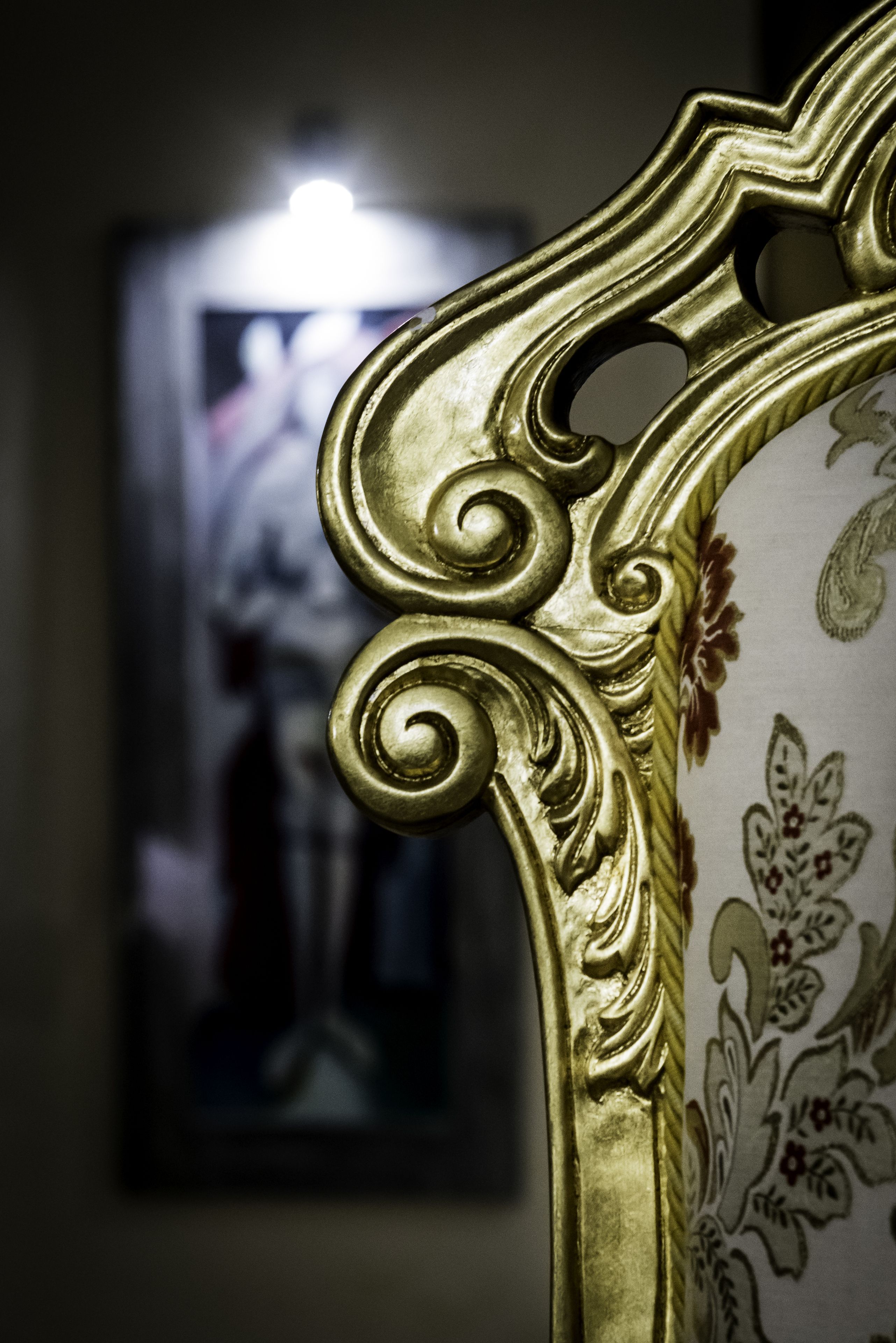 Un gros plan d’un fauteuil orné de motifs floraux et de détails dorés sur le revêtement.
