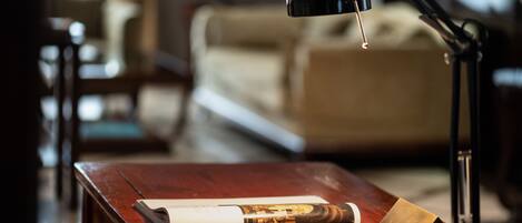 A wooden desk with a book, a rolled-up magazine, and a lamp.