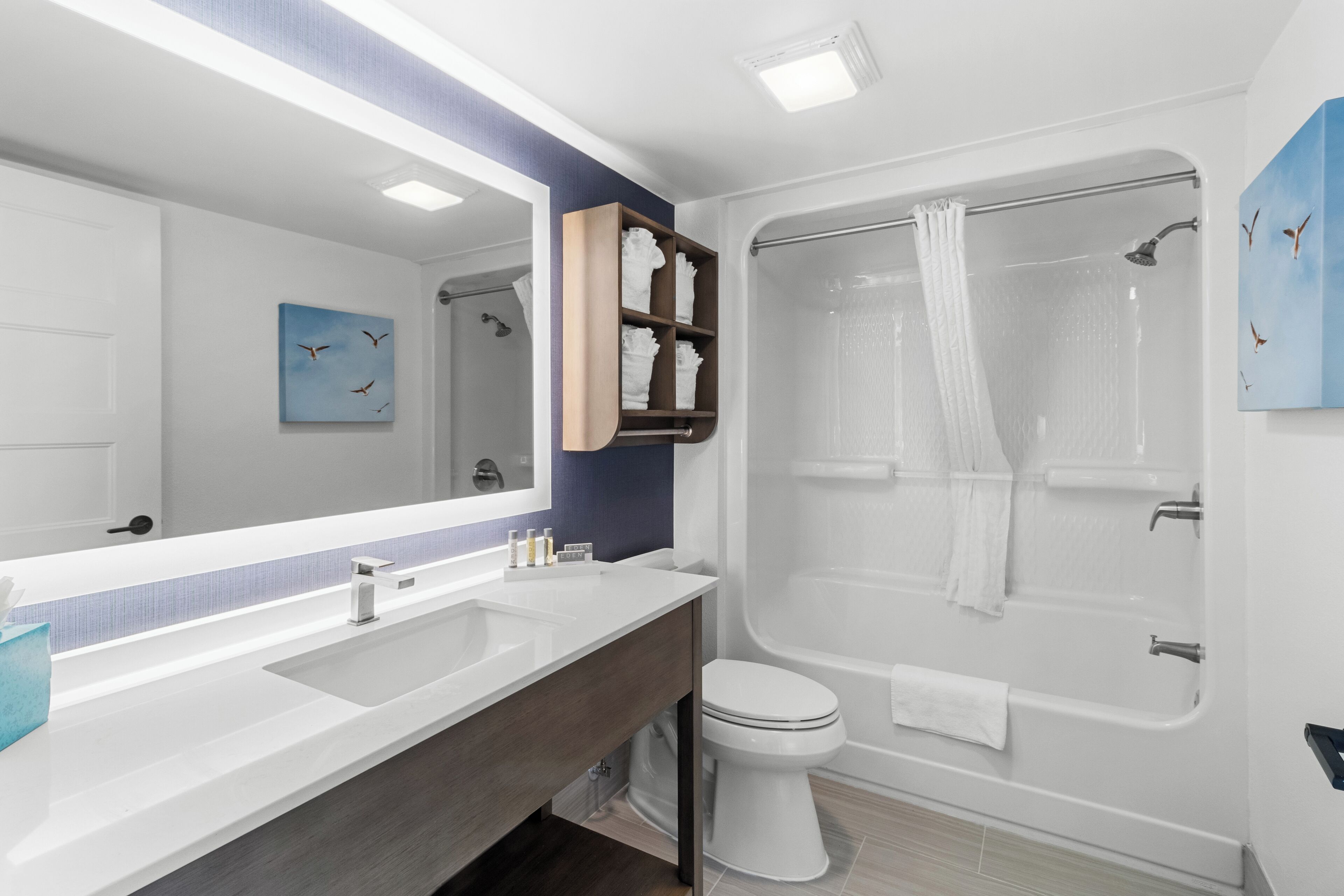 Un baño moderno con un espejo grande, una bañera y un inodoro.
