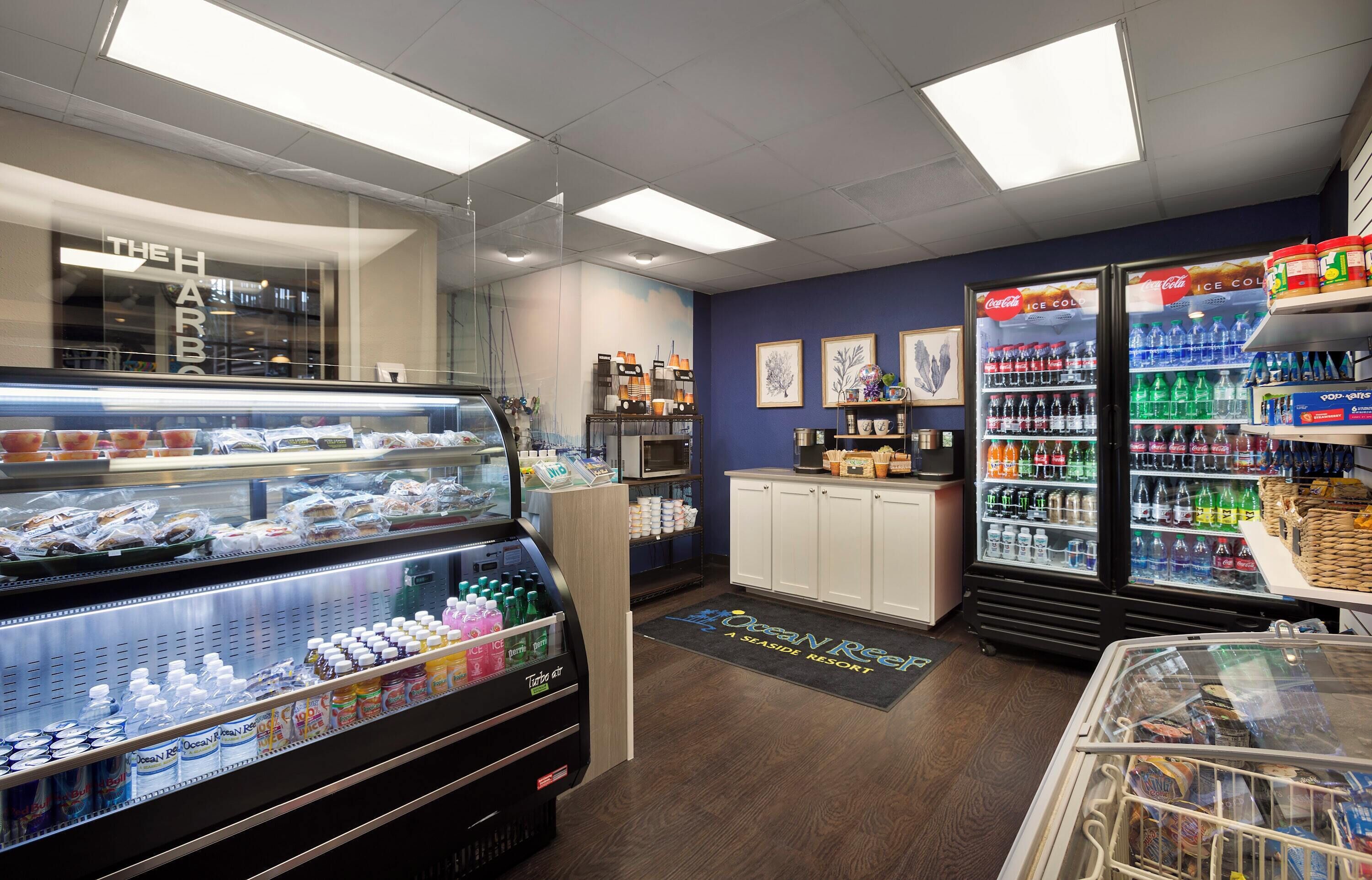 Une vitrine réfrigérée contenant divers produits alimentaires, un réfrigérateur Coca-Cola et un congélateur.