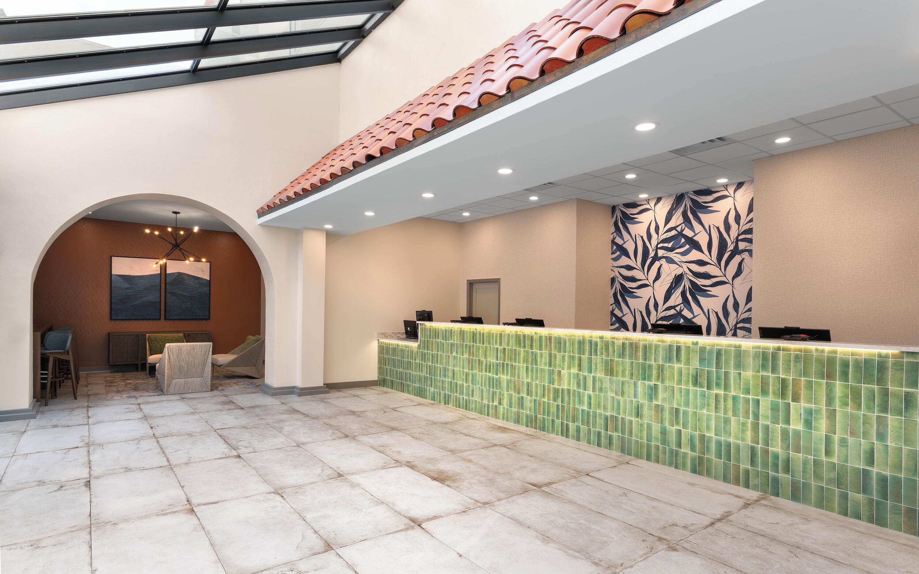 A hotel lobby with a reception desk, seating area, and a large wall mural.