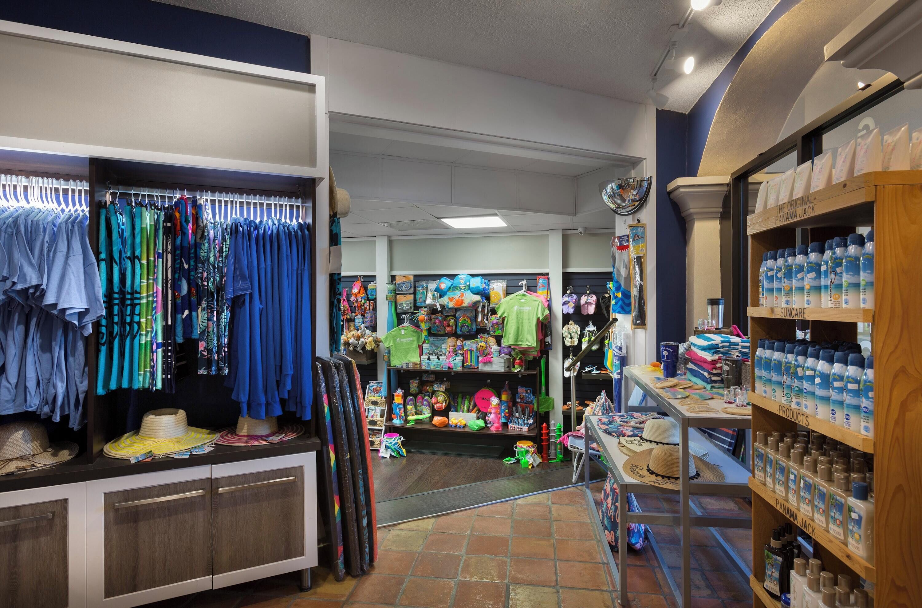 A store with clothing racks, shelves with various items, and a section with bottled water.