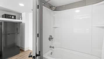 A modern bathroom with a glass shower enclosure, a built-in toilet, and a stainless steel refrigerator.