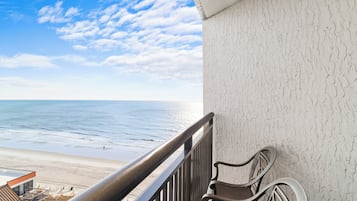 A balcony with a view of the beach and ocean.