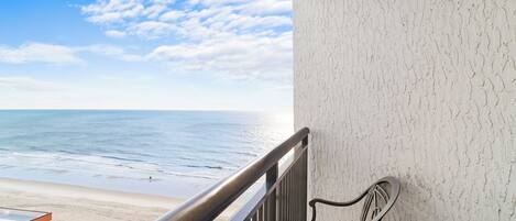 A balcony with a view of the beach and ocean.