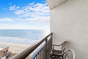 A balcony with a view of the beach and ocean.