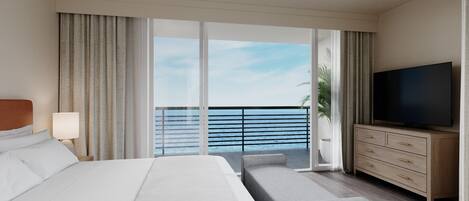 A hotel room with a large bed, a TV, a sofa, a wooden dresser, and a balcony with a view of the sea.