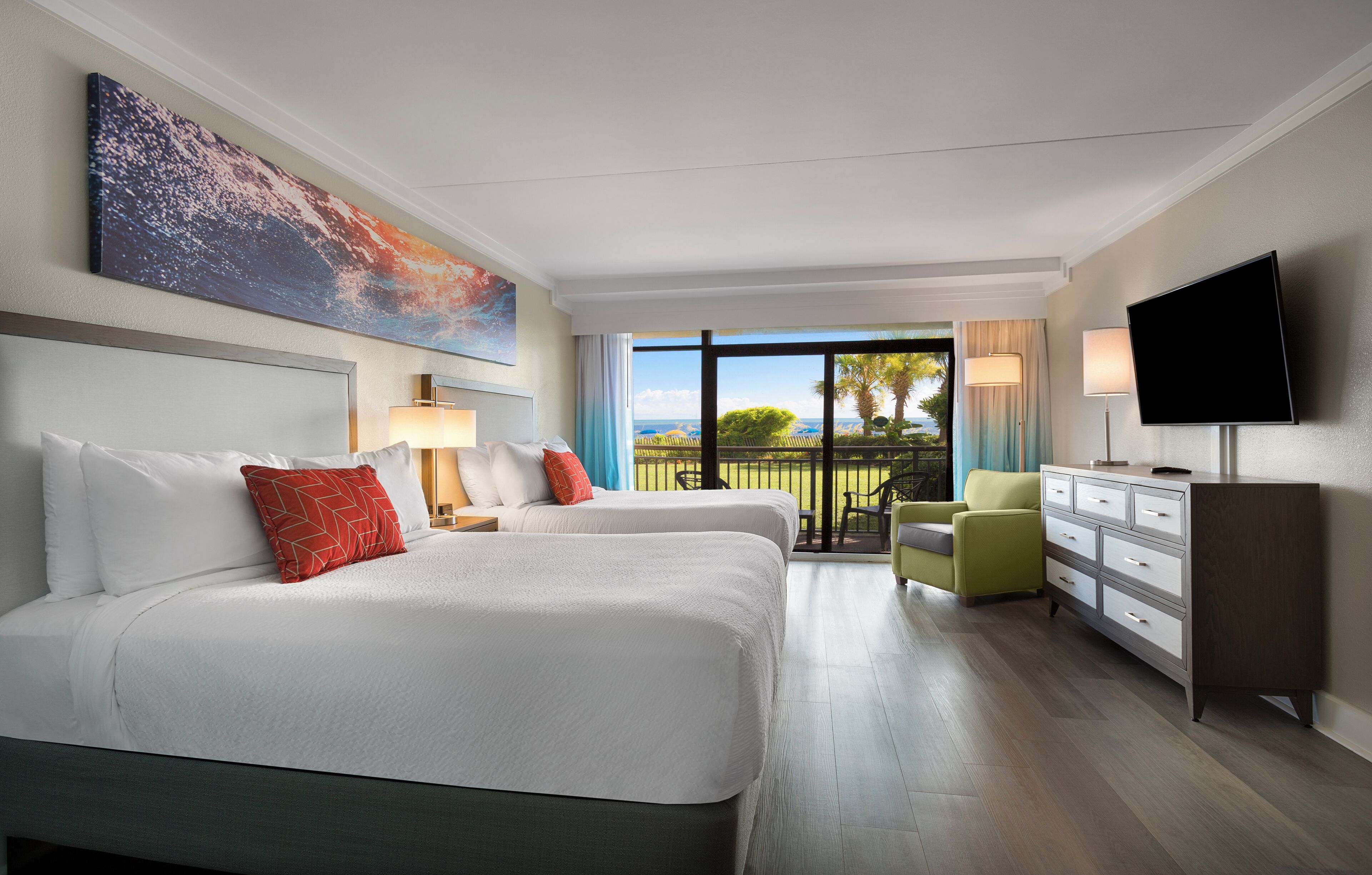 A hotel room with two beds, a TV, a dresser, and a balcony with a view.