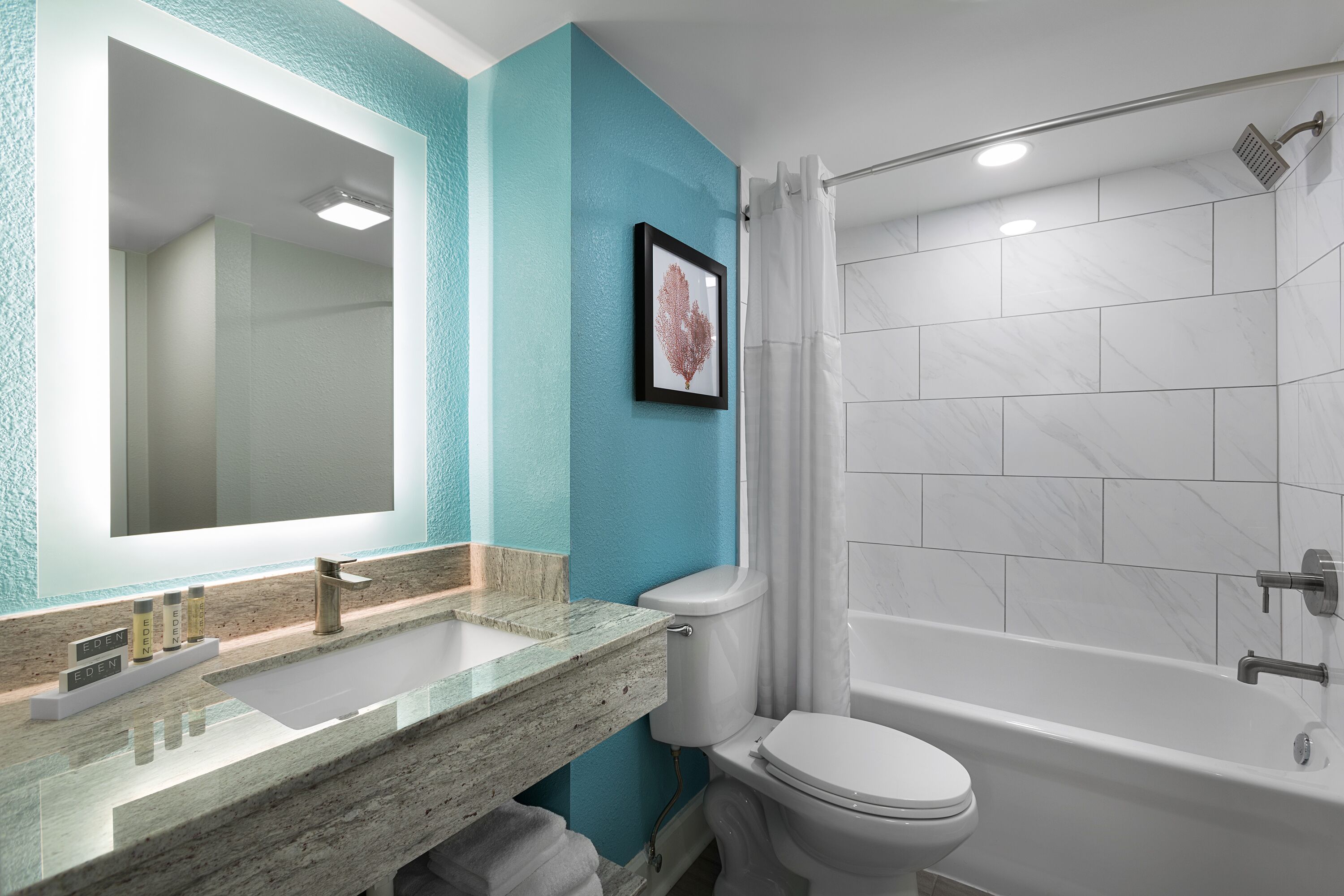 Un bagno con un ampio specchio, un lavandino, un water e una doccia.