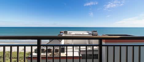 A balcony with a view of the sea and a building with air conditioning units.