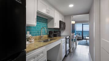 Una cocina moderna con armarios blancos, un refrigerador negro y un salpicadero verde azulado.