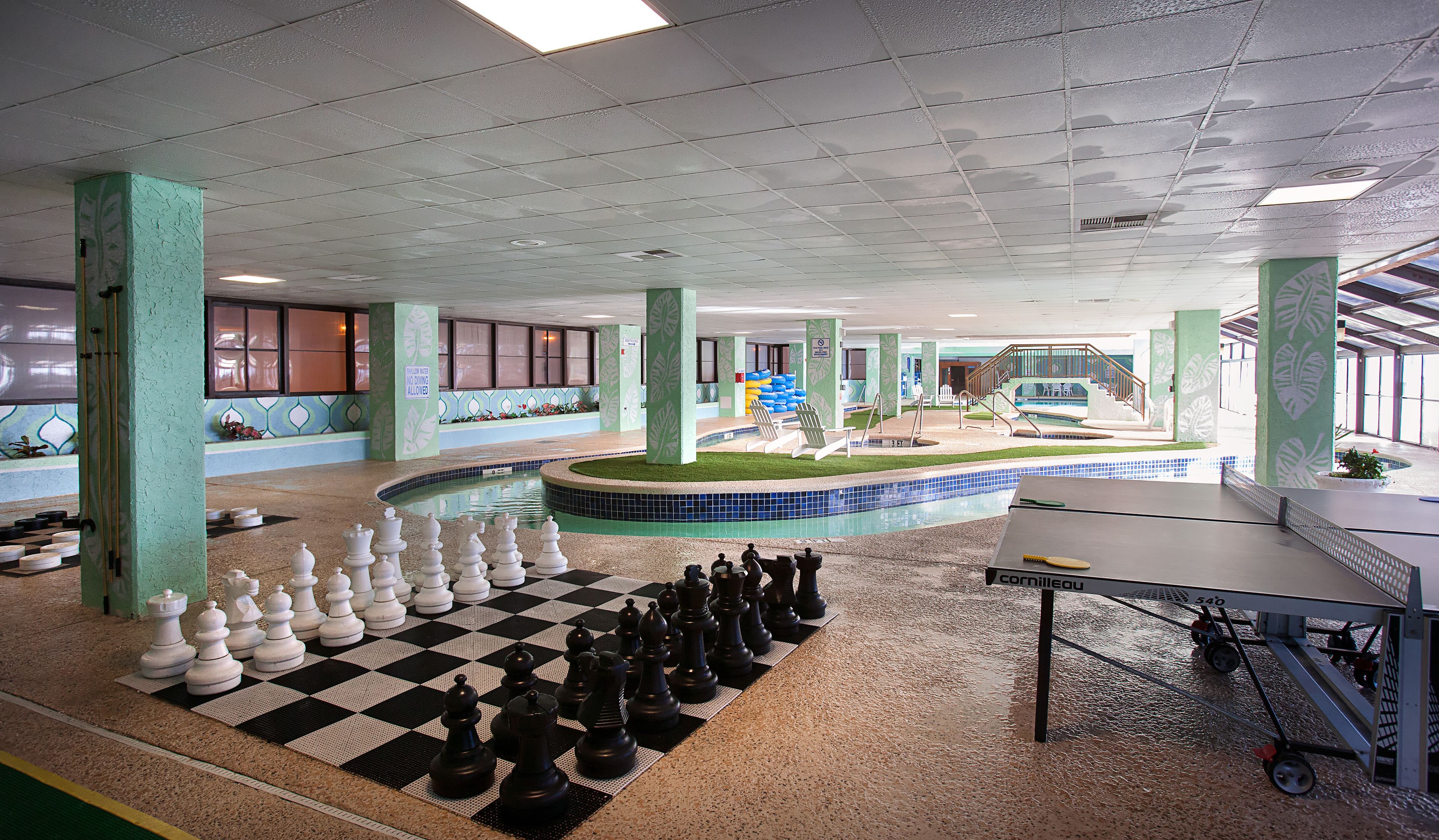 Un espacio interior amplio con piscina, un juego de ajedrez y una mesa.