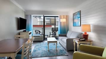 Ein modernes Wohnzimmer mit Essbereich, einer Couch, einem Fernseher und einem Balkon mit Geländer.