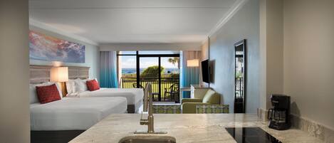 Habitación de hotel con cocina, dos camas, televisor y balcón con vistas.