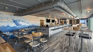 Un restaurante con un mural de olas, zona de bar y diversas opciones de asientos.