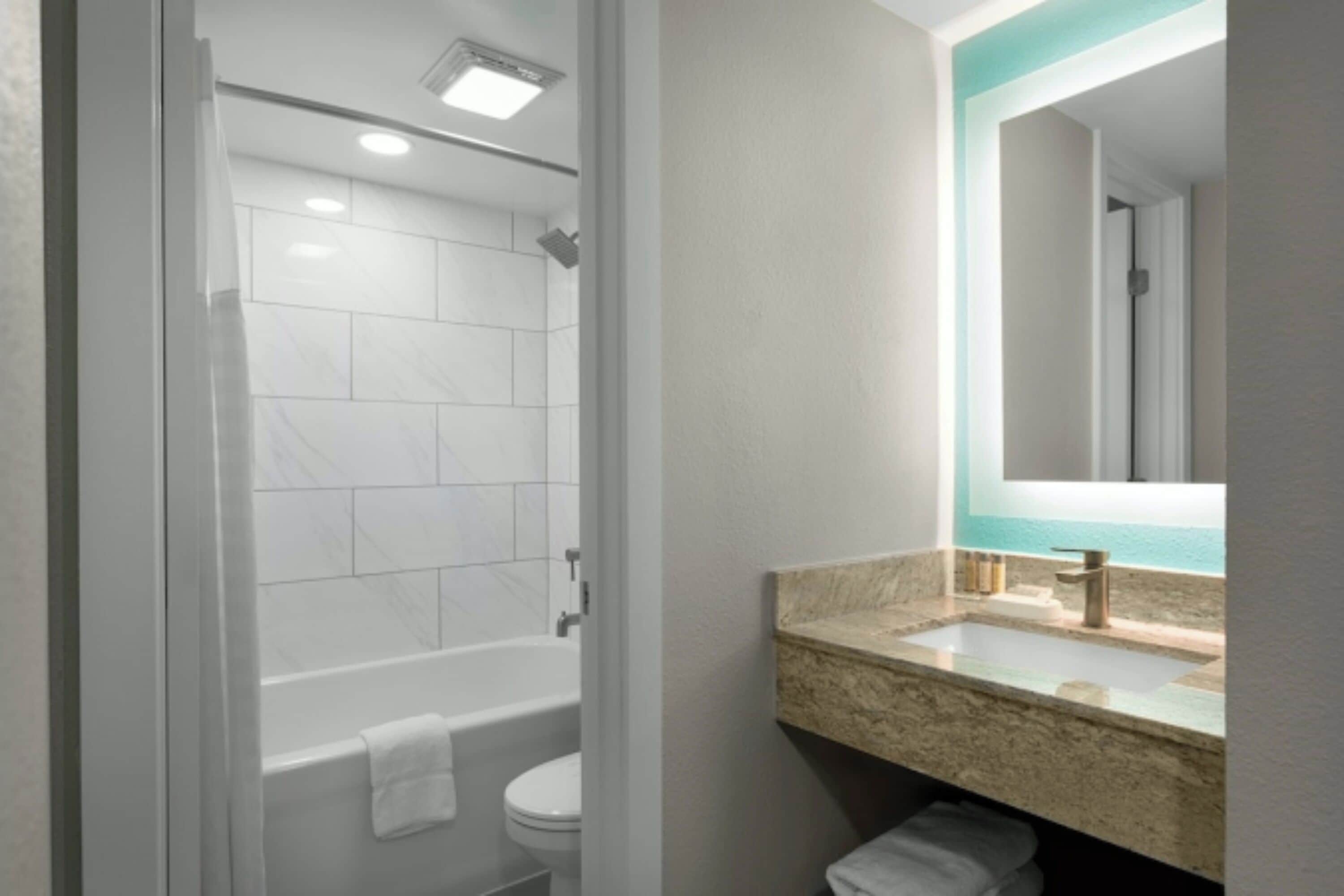 Une salle de bain moderne dotée d’une douche à parois de verre, d’une baignoire, de toilettes et d’un lavabo avec un plan de travail en marbre.