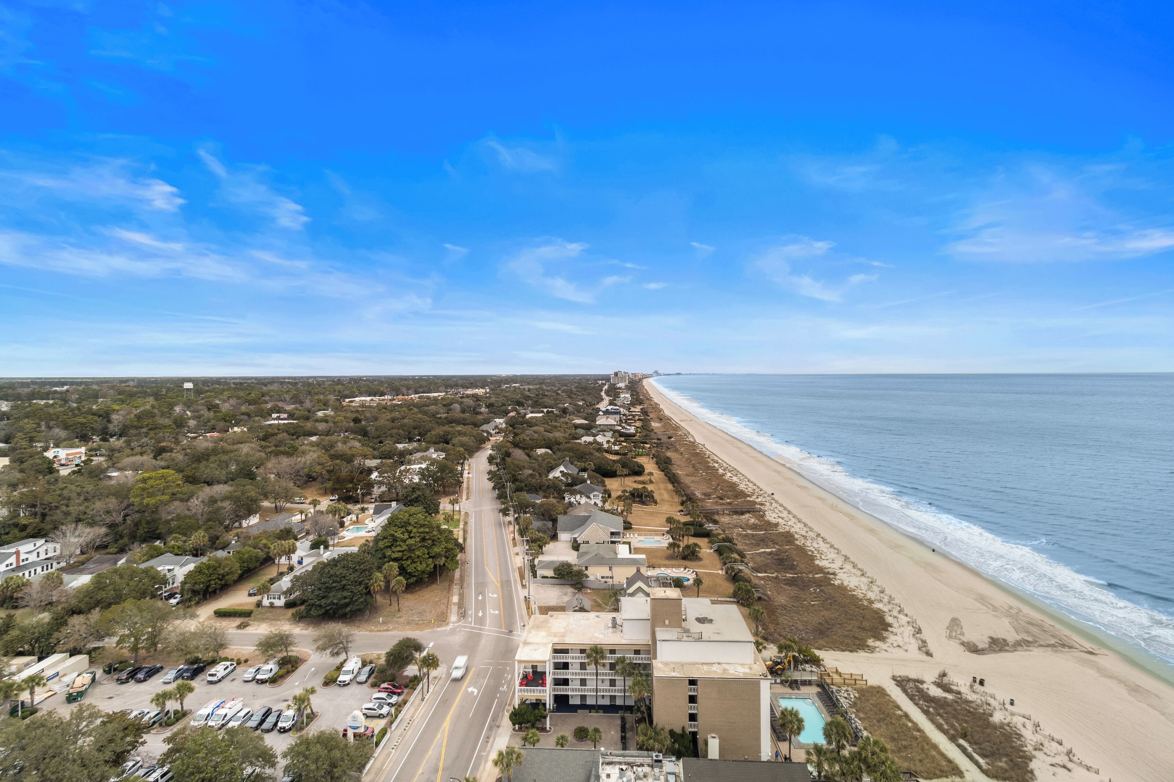 An aerial view of a coastal town with a beach, roads, and buildings.
