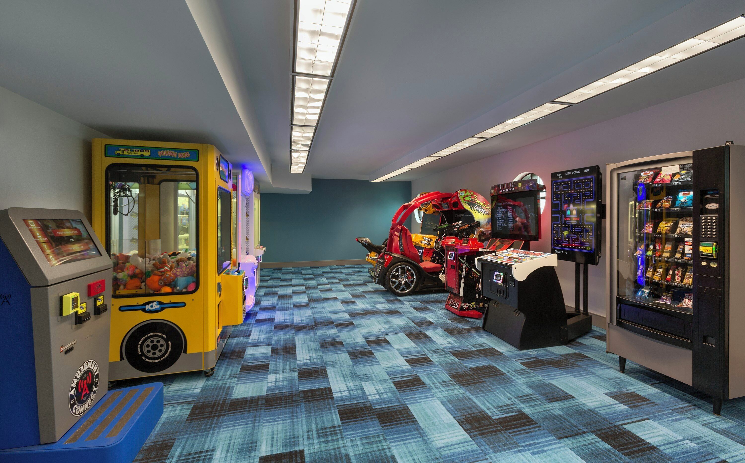 A hallway with arcade games, a claw machine, and a vending machine.