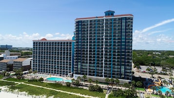 Un hotel moderno de gran altura con varios balcones, piscina y parque acuático.