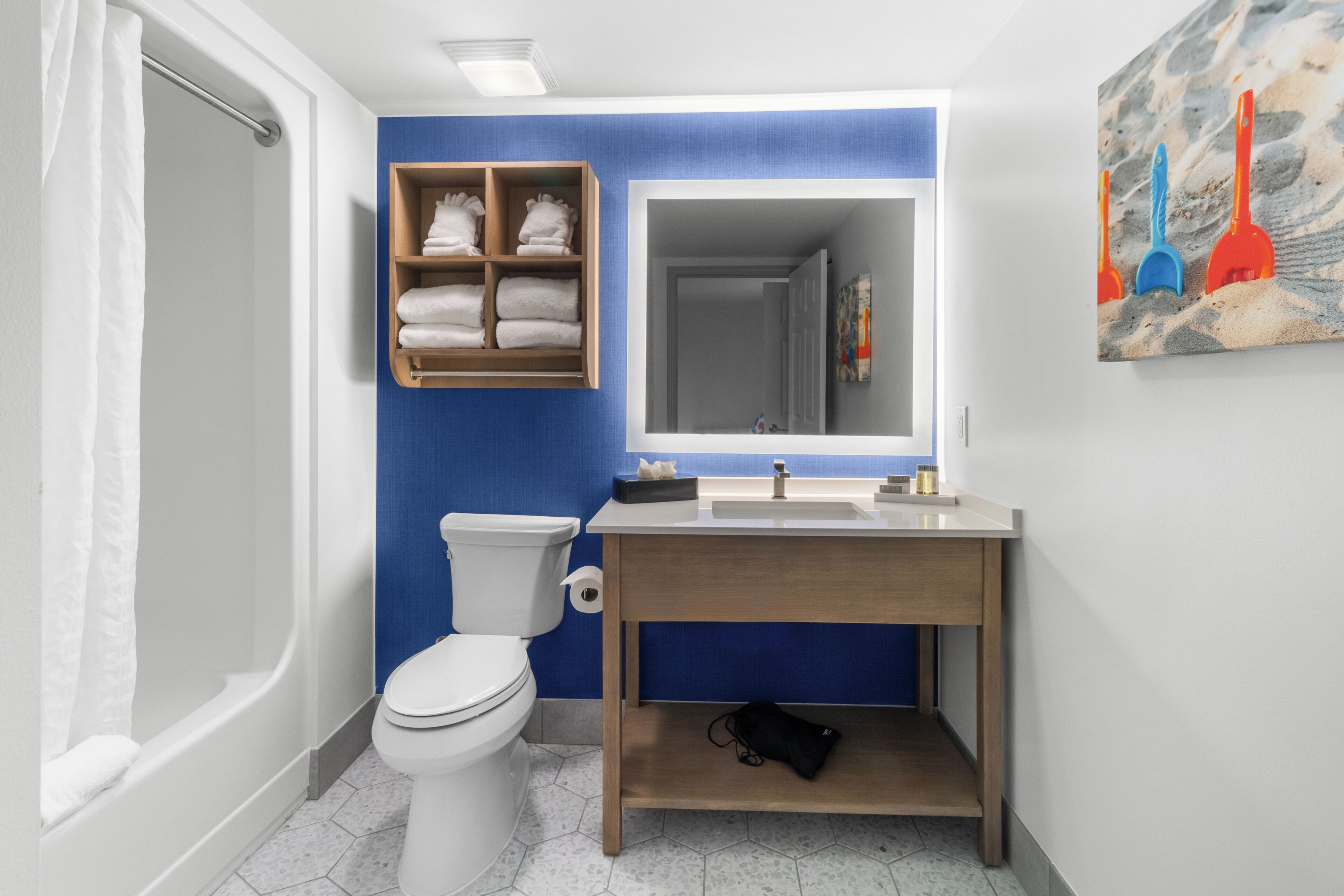 A bathroom with a white toilet, a wooden vanity with a sink, and a blue accent wall.