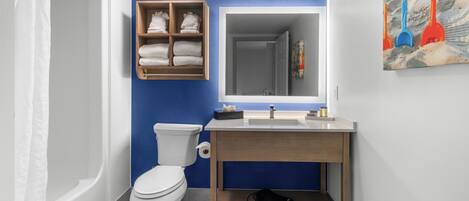 A bathroom with a white toilet, a wooden vanity with a sink, and a blue accent wall.
