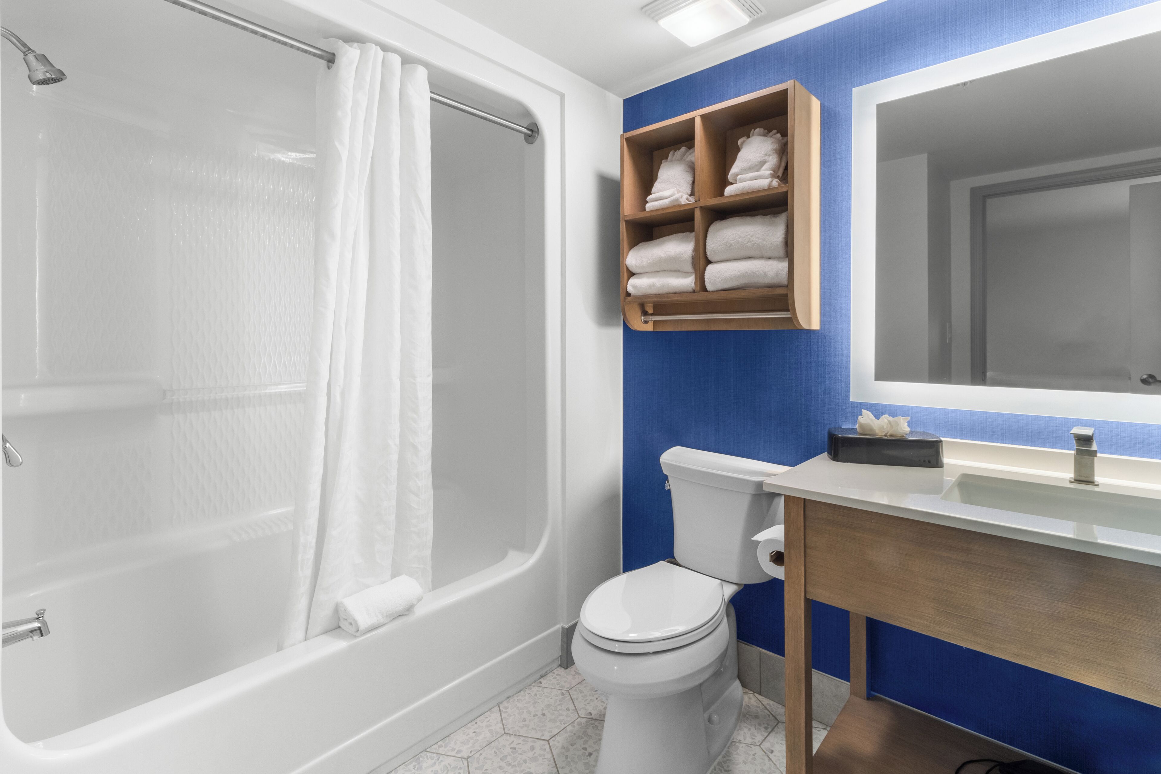 Un baño moderno con bañera, inodoro y tocador con espejo.
