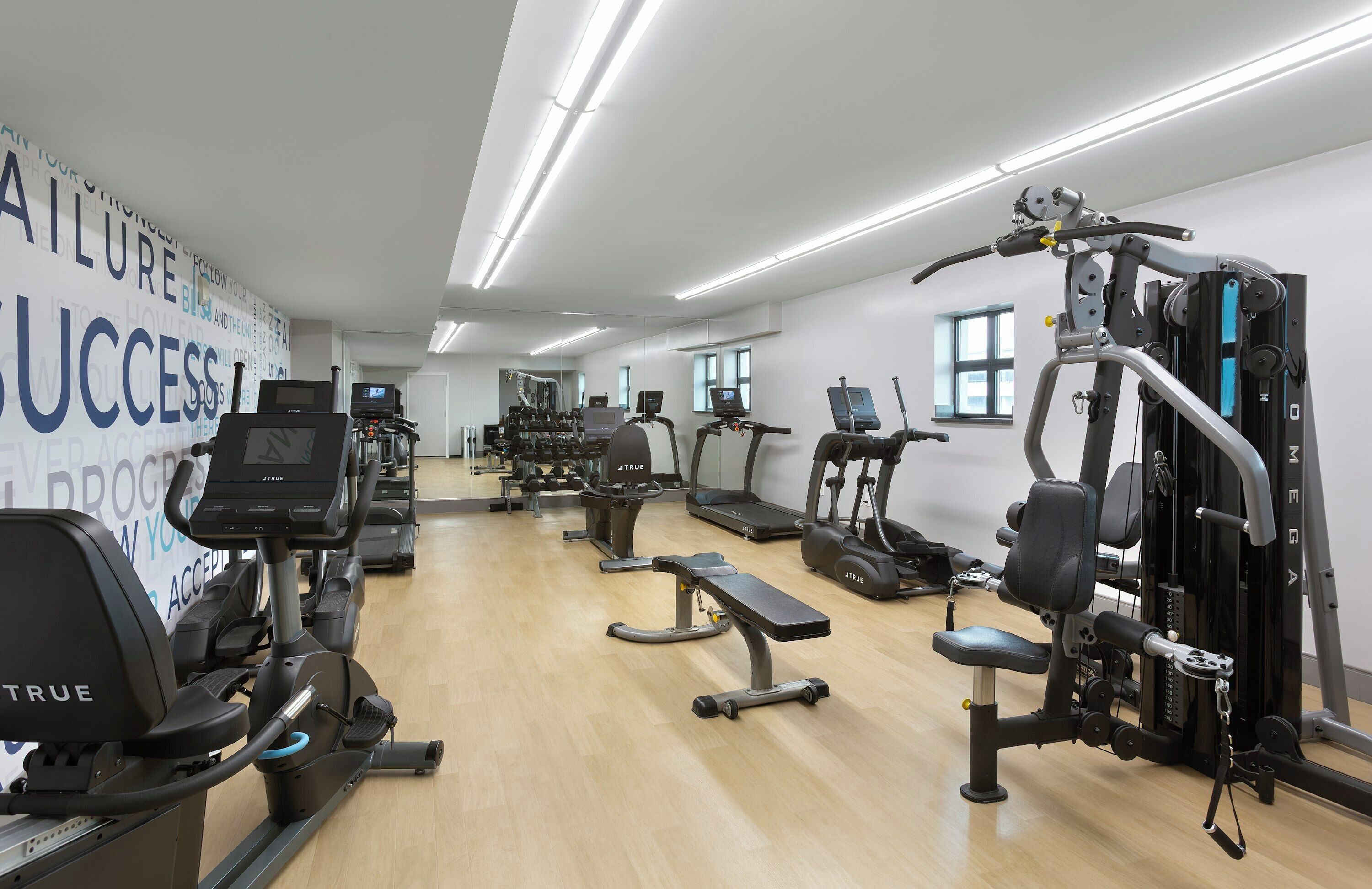 A gym with various exercise equipment, including treadmills, stationary bikes, and weight machines.