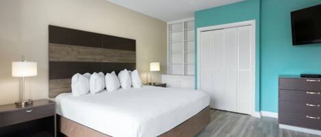 A modern hotel room with a large bed, a ceiling fan, a TV, and a wardrobe.