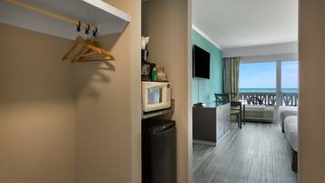 A hotel room with a balcony, a microwave, a refrigerator, a desk, and a bed.