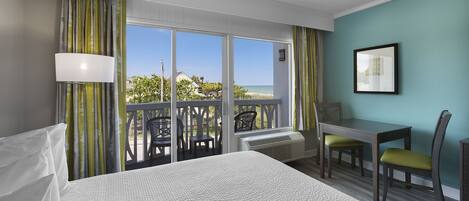 Una habitación de hotel con cama, escritorio, dos sillas, ventana con vistas al exterior y un cuadro en la pared.
