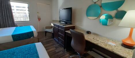 A hotel room with two beds, a desk, a chair, a television, and a wall with decorative mirrors.