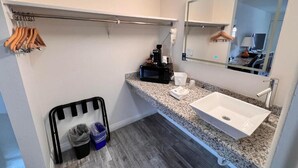 A bathroom with a white sink, a mirror, a towel rack, and a hairdryer. - Howard Johnson by Wyndham Reno Downtown (Reno)