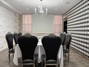 A conference room with a white table, black chairs, a chandelier, and a patterned wall.