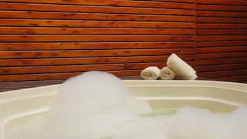 A hot tub with bubbles, a wooden wall, and towels.