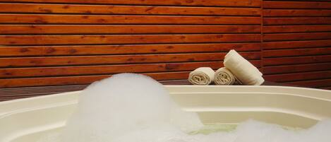 Un jacuzzi con burbujas, una pared de madera y toallas.