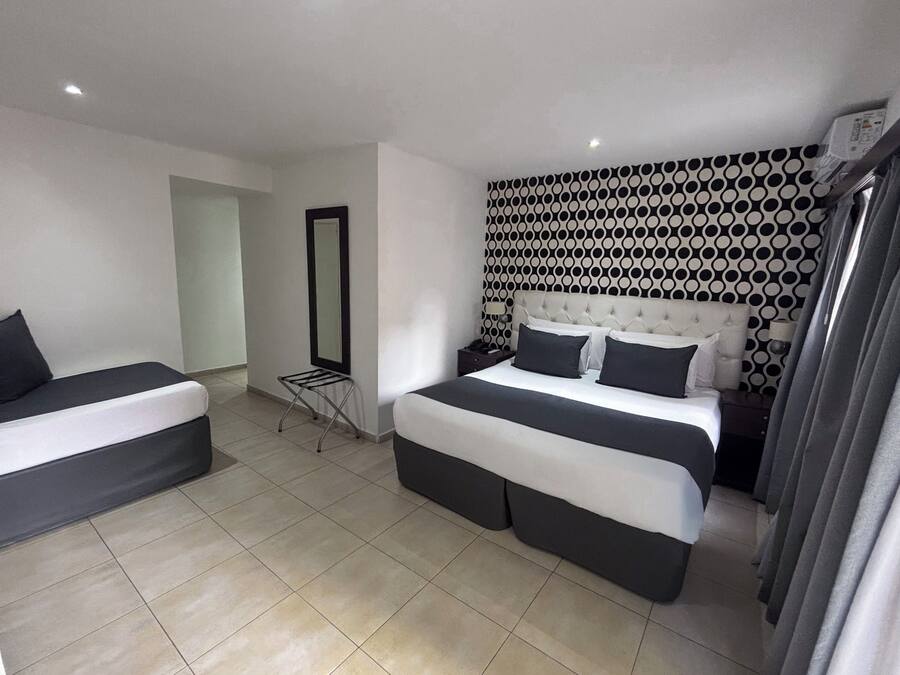 A bedroom with two beds, a mirror, and a patterned wall.