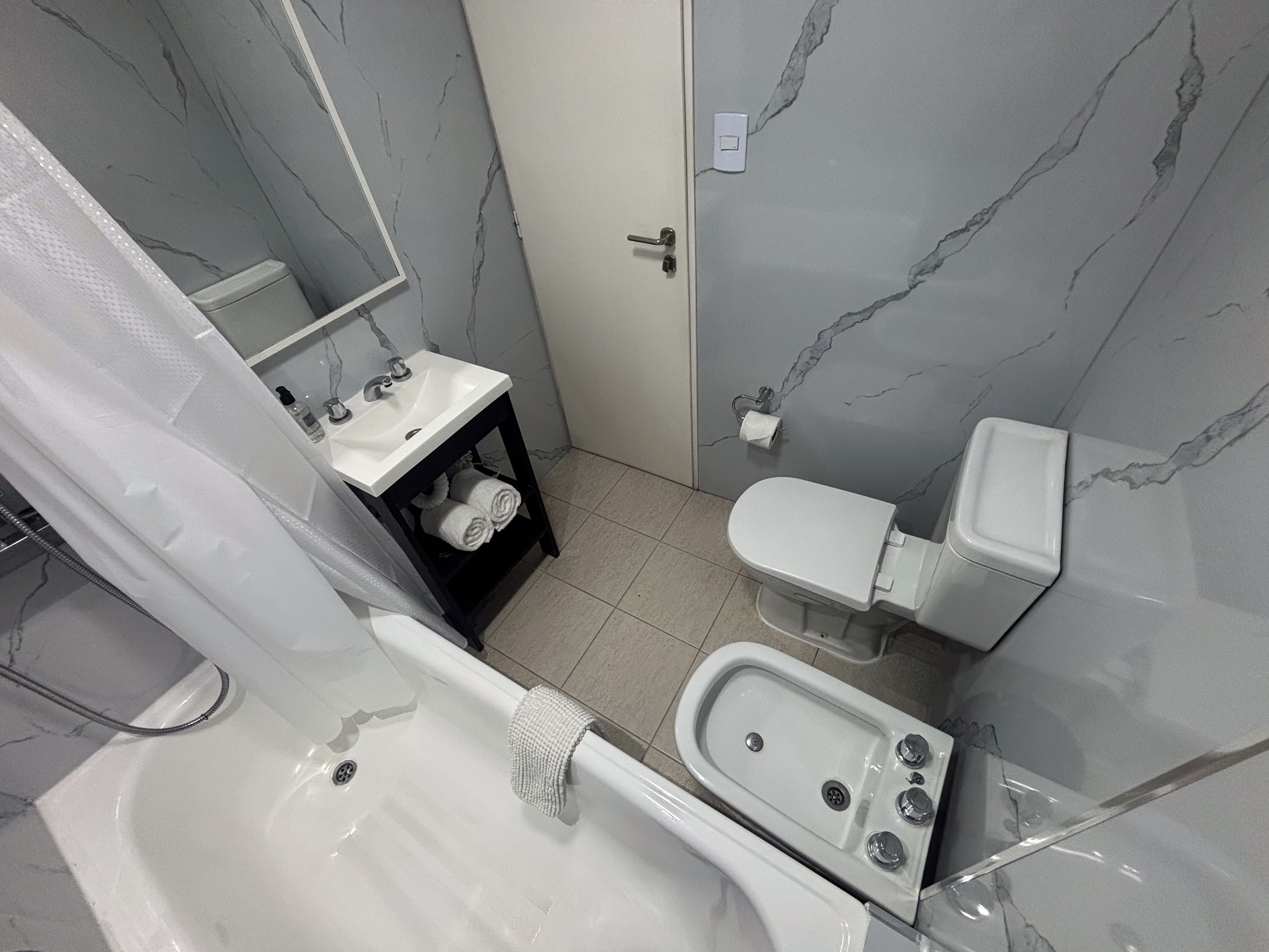 A bathroom with a bathtub, toilet, sink, and a shower area.
