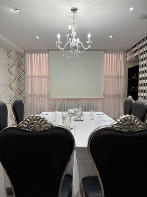 A conference room with a long table, chairs, a projector screen, and a chandelier. - Ker Belgrano Hotel (Buenos Aires)