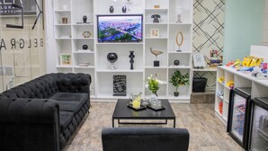 A modern living room with a black sofa, a television, and a coffee table with decorative items.