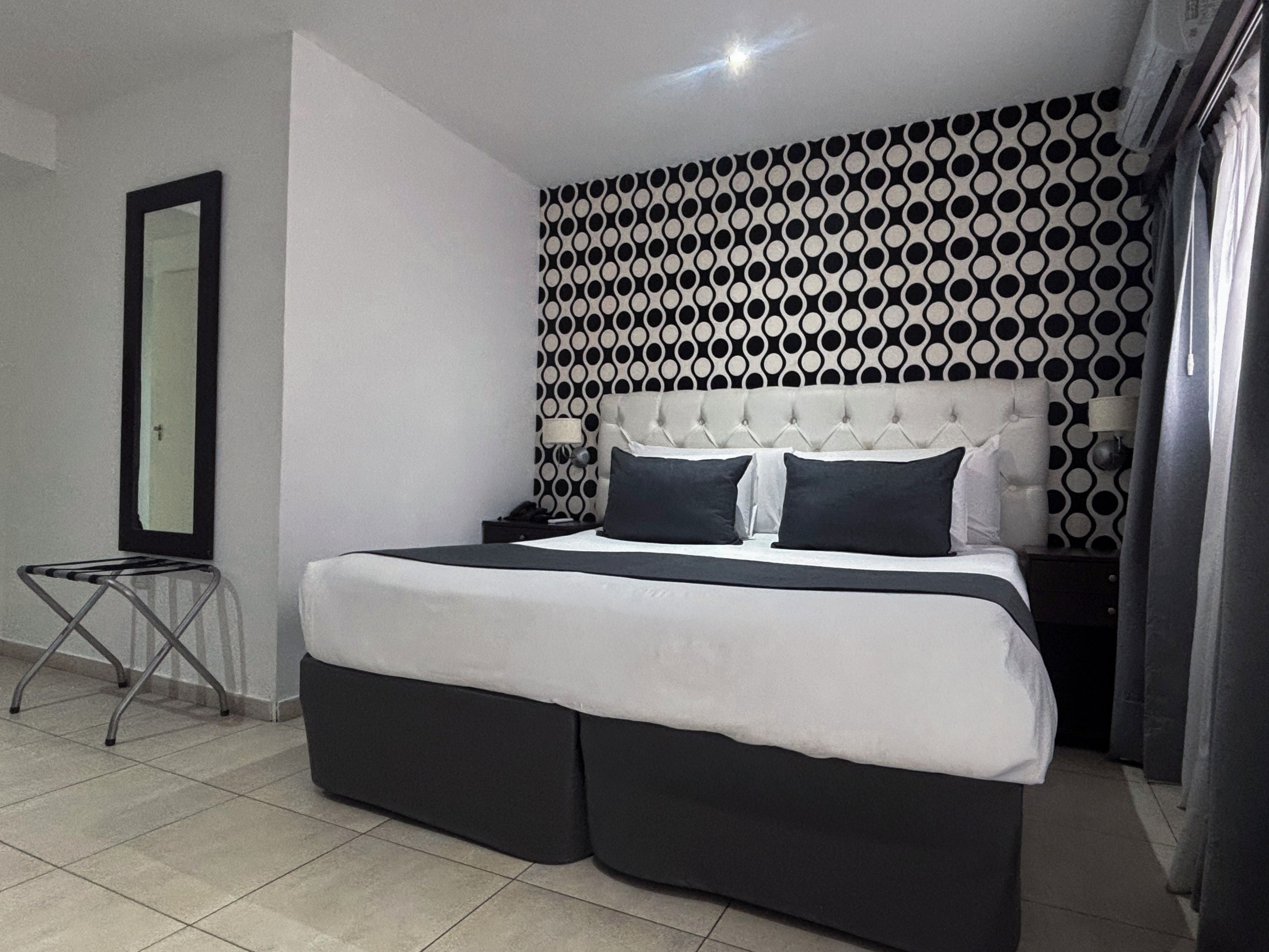 Ein modernes Schlafzimmer mit einem großen Bett, einem Spiegel und einer Wand mit Muster.