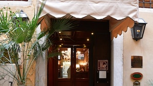 A hotel entrance with a dark wooden door, a tiled entrance, and a sign indicating it is a hotel.
